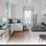 Eco-conscious cabinetry featuring low-VOC finishes on a custom matte white shaker-door kitchen with handles.